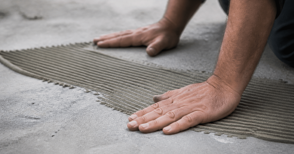 Mains applicant adhesif sur surface beton grise avant fixation bois