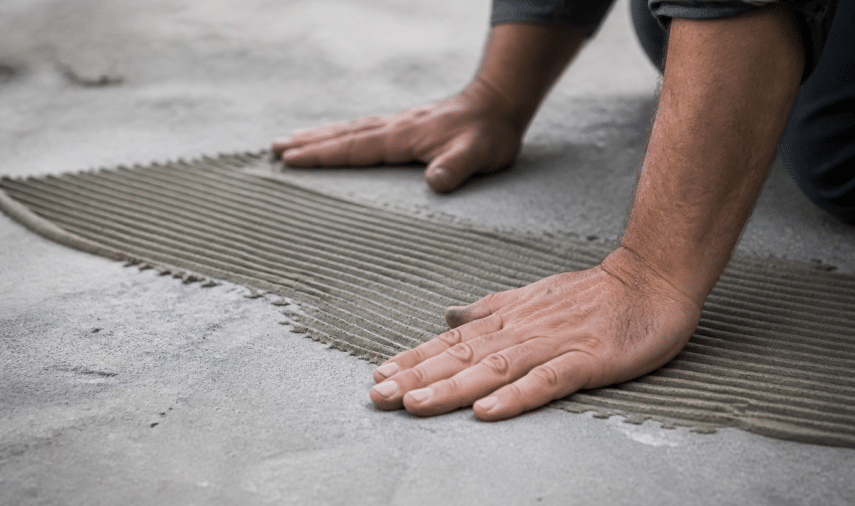 Mains applicant adhesif sur surface beton grise avant fixation bois